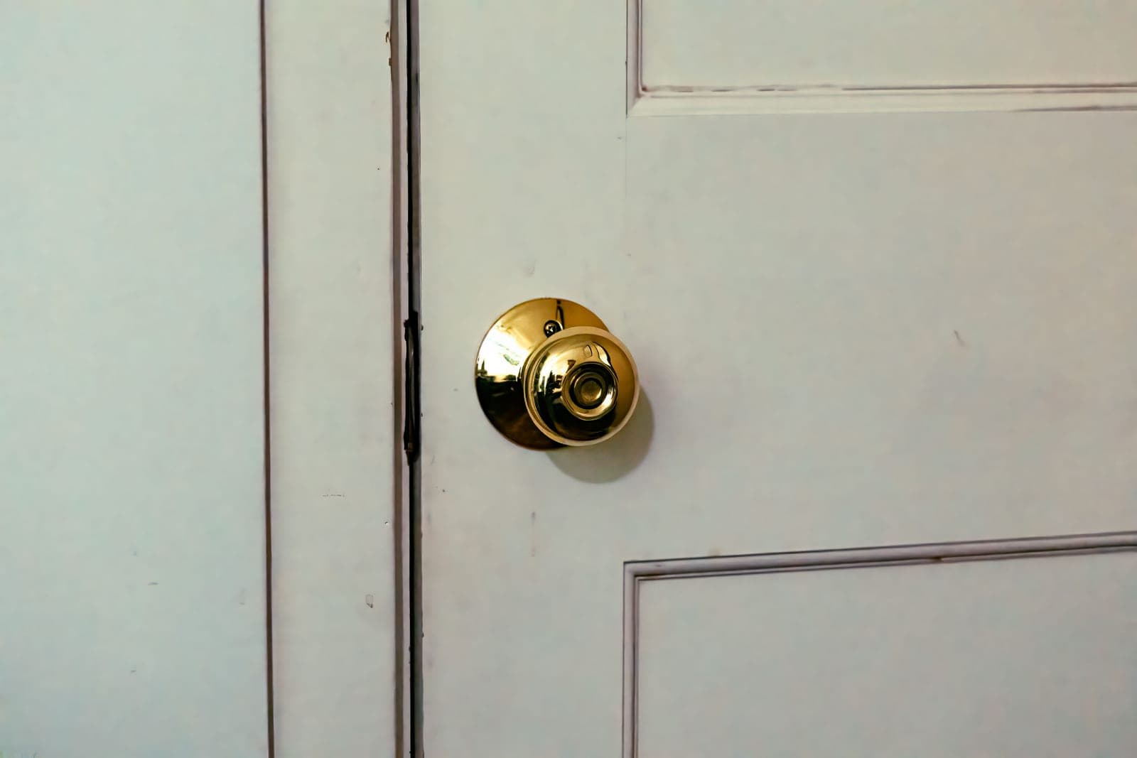 A classic white panelled front door with a polished brass handle and deadbolt